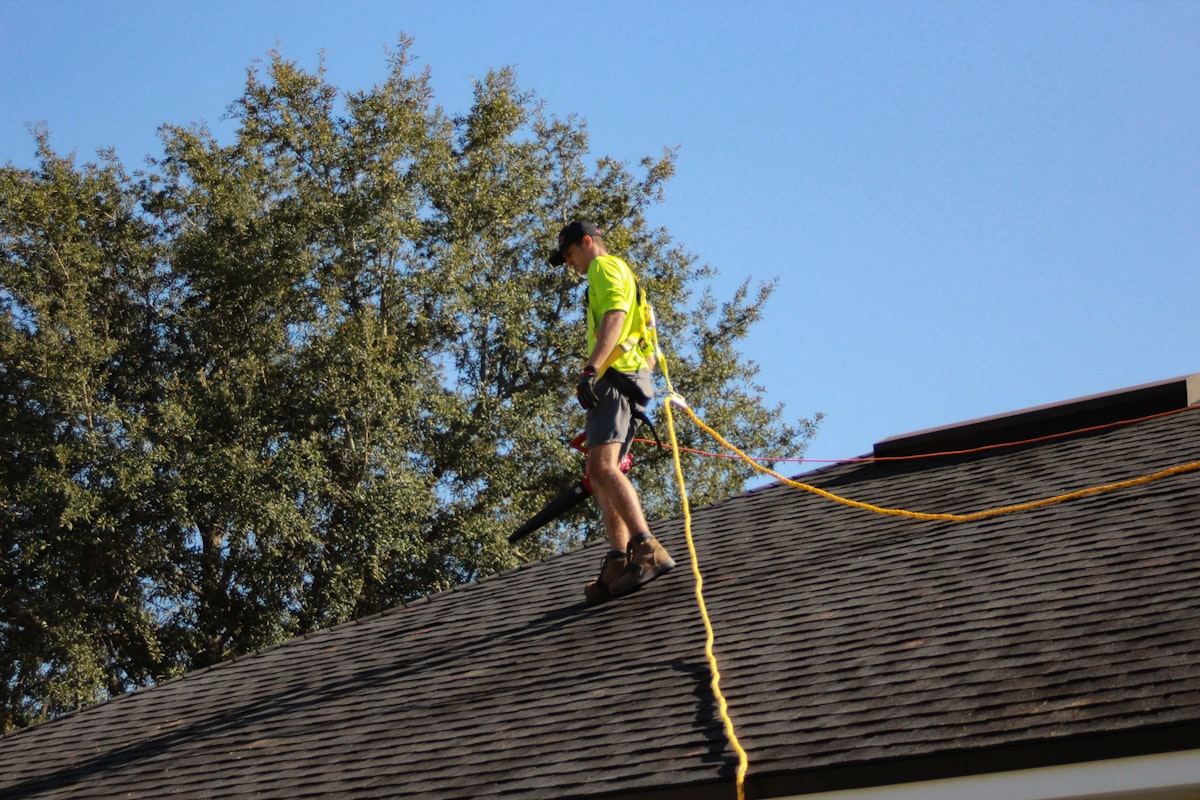 Technician on an asphalt shingle roof during a soft wash